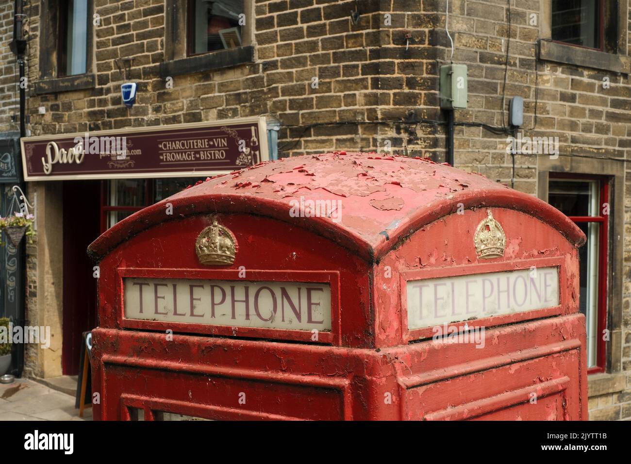 Haworth, West Yorkshire, UK. Paint peeling on a traditional red telephone box on Main Street Haworth. Stock Photo