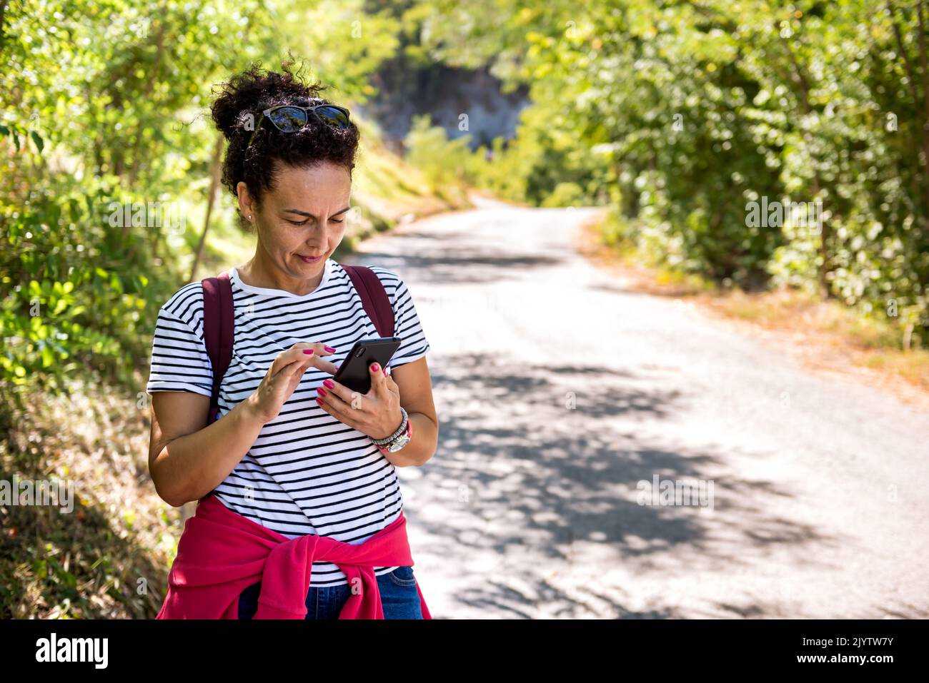 Woman tourist use navigation on the smartphone while hiking on summer sunny day. Stock Photo