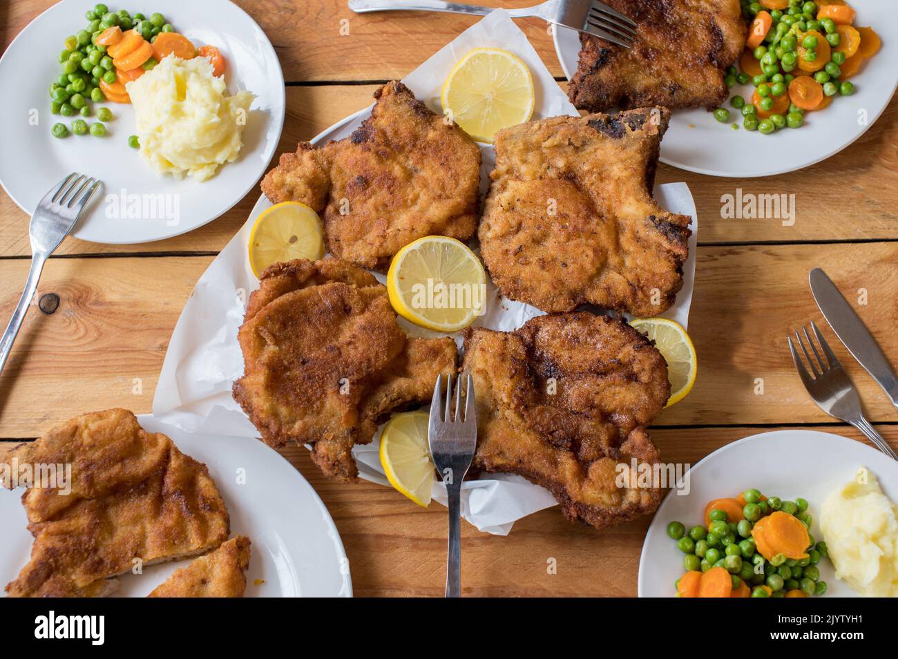 Family dinner table with breaded pork chops or cutlets, mashed potatoes and vegetables Stock Photo