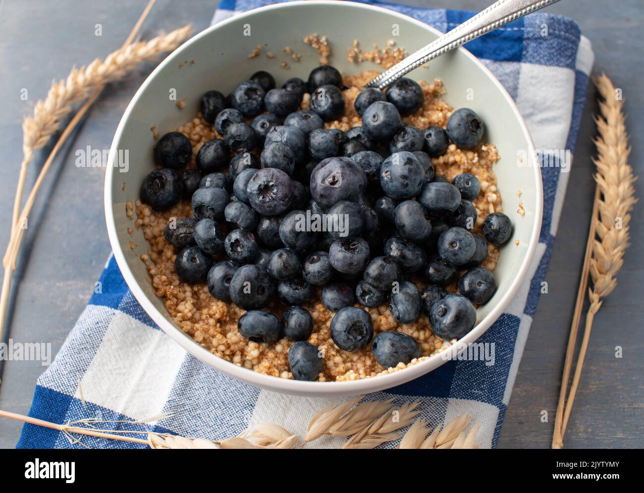 Breakfast cereal porridge with oats, amaranth, quinoa and fresh blueberries in a bowl with spoon Stock Photo