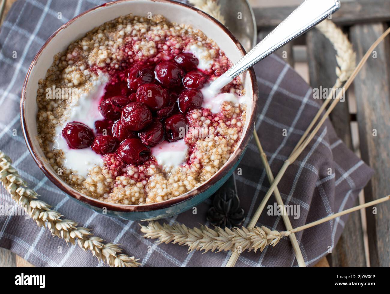 Breakfast cereal porridge with oats, amaranth, quinoa, yogurt and cooked cherries Stock Photo