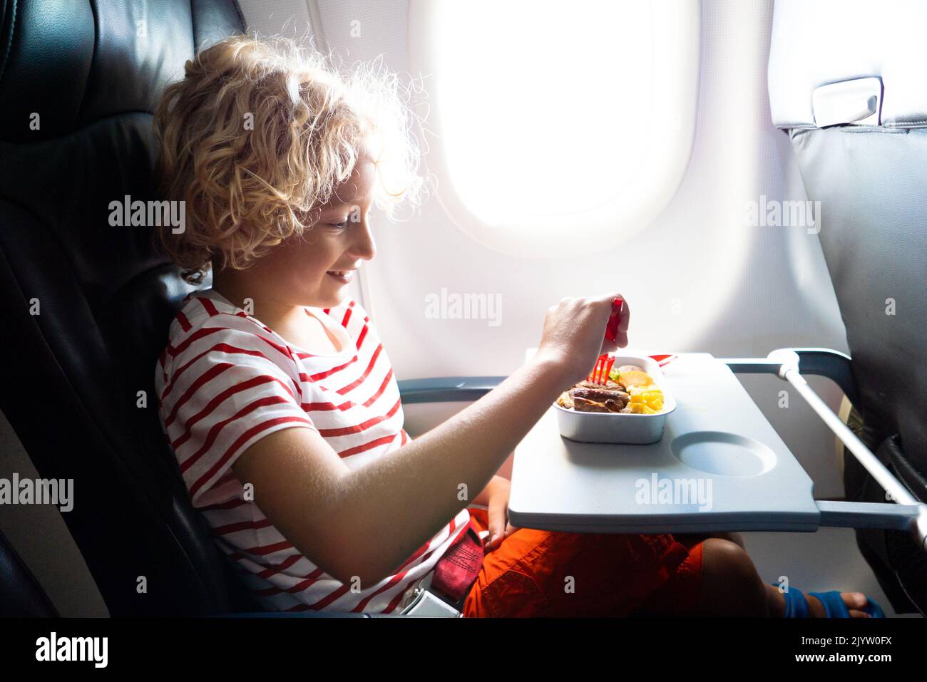 Child in airplane window seat. Kids flight meal. Children fly. Special