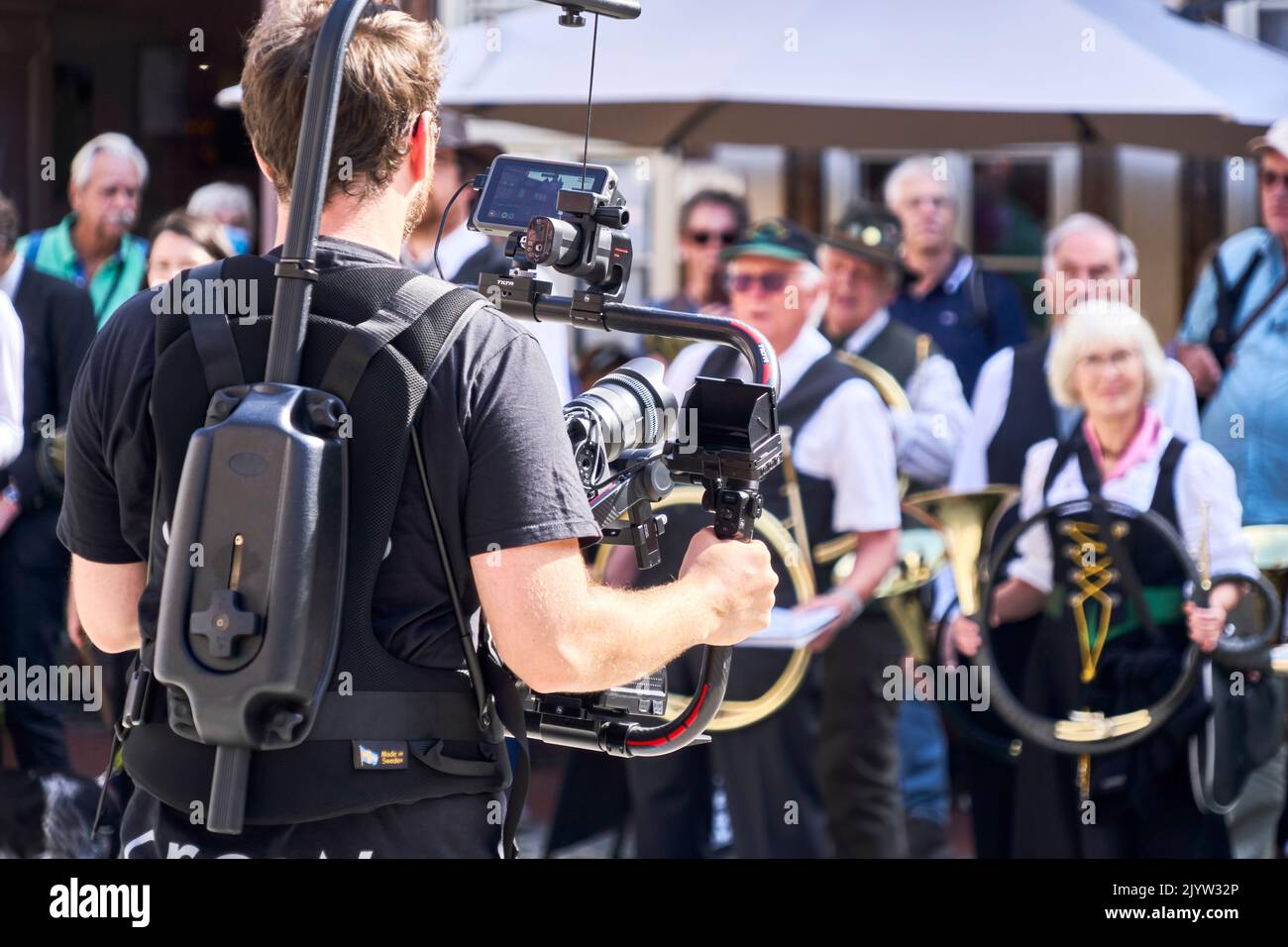 Stolberg, Germany, September 4, 2022: Professional cameraman with big gimbal in front of body filming traditional costume group in Harz mountains Stock Photo