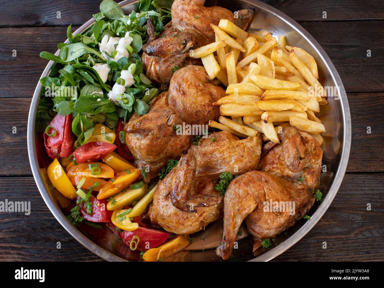 Oven baked chicken with salad and homemade french fries on a large platter Stock Photo