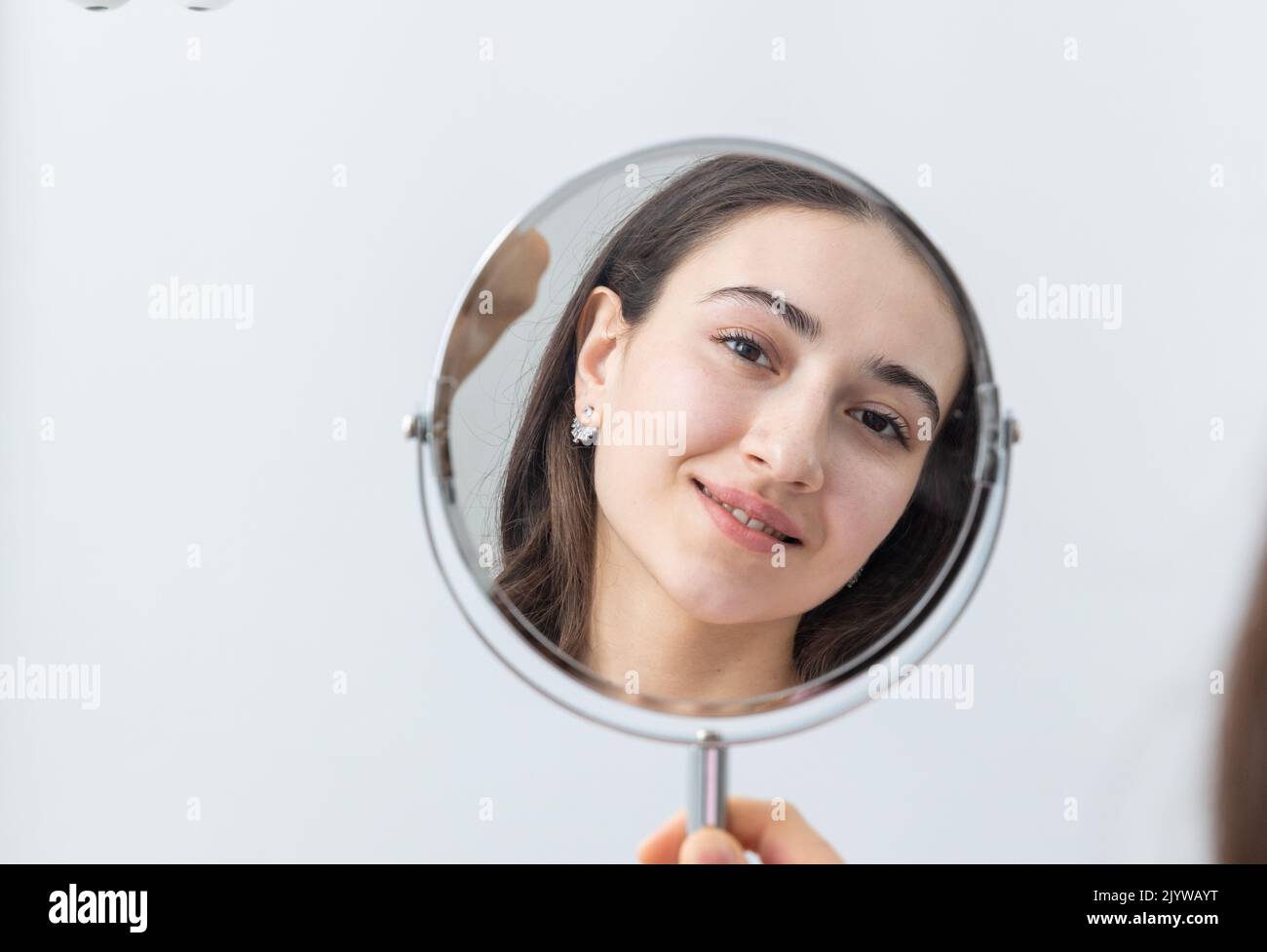 Young woman looking in the mirror after a dental procedure Stock Photo ...