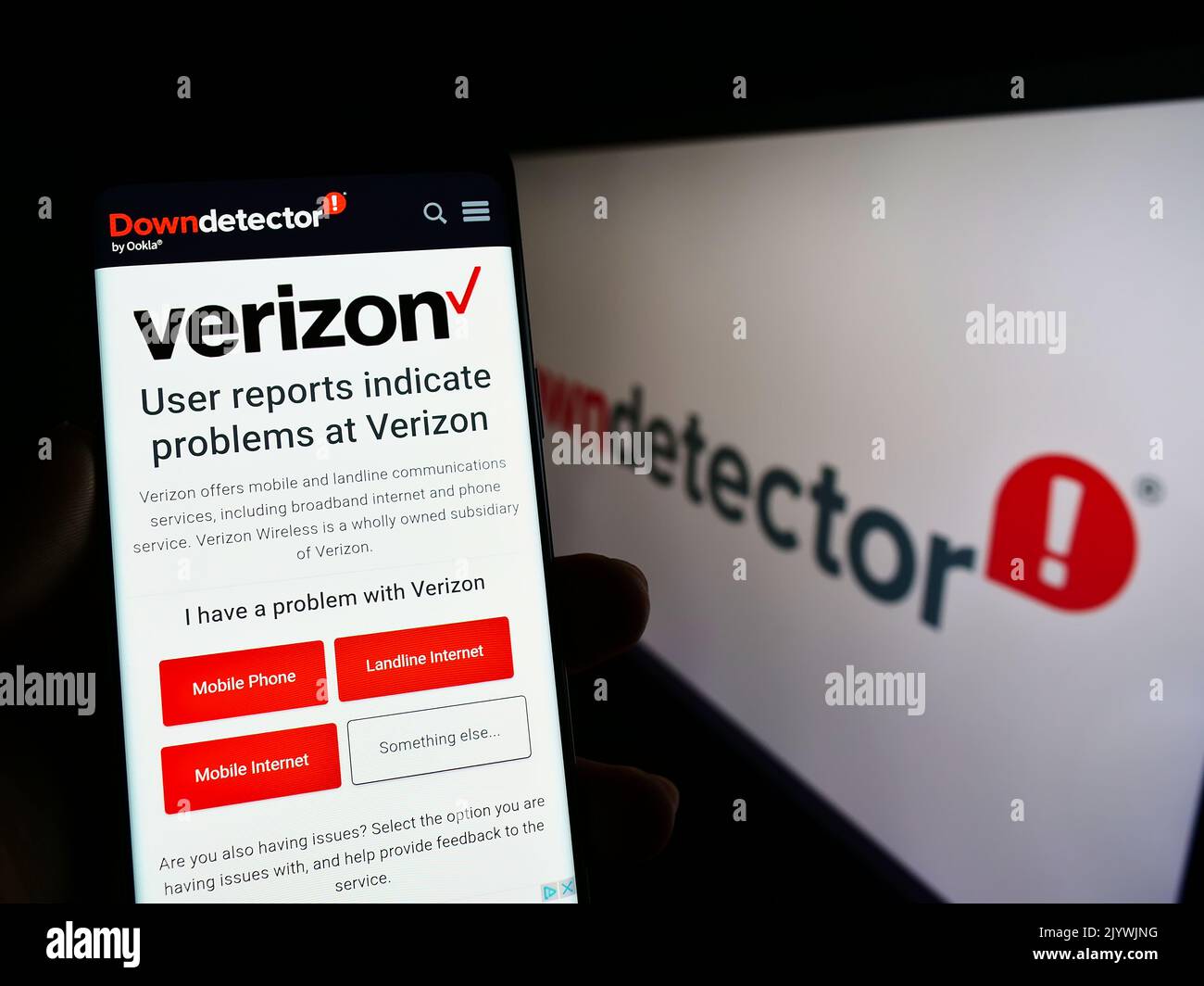 Person holding smartphone with website of platform Downdetector and