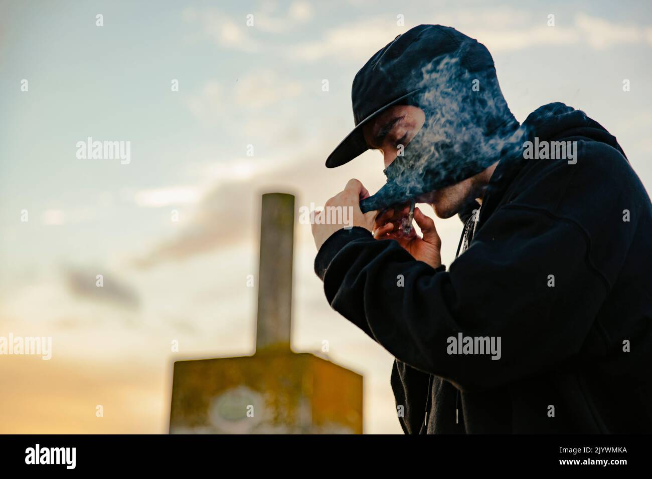 Guy with balaclava smoking a joint of marijuana outdoors Stock Photo