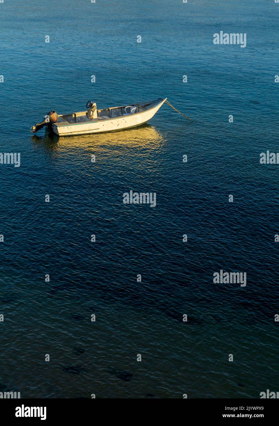 An old motor boat is anchored in the bay at sunset Stock Photo - Alamy