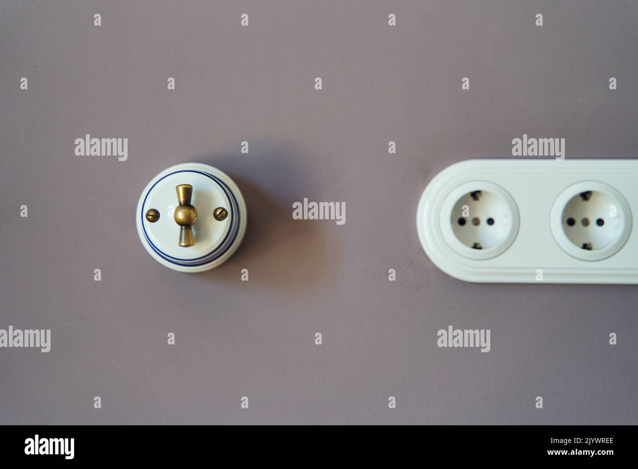Retro style light switch and socket on dark pink wall Stock Photo