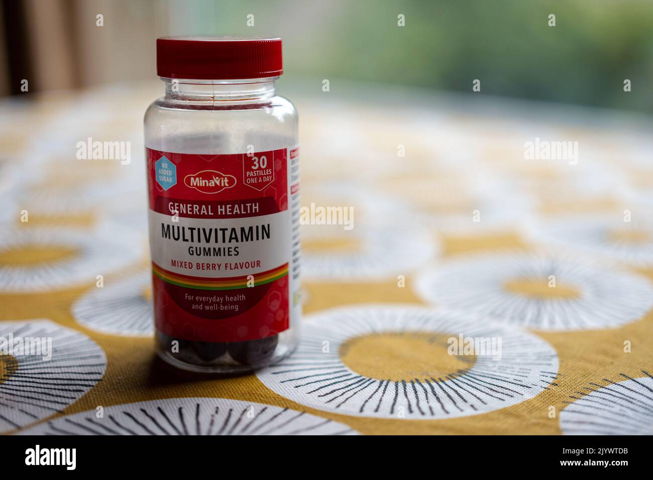 A bottle of mixed berry flavor multivitamin gummies on a table. Stock Photo