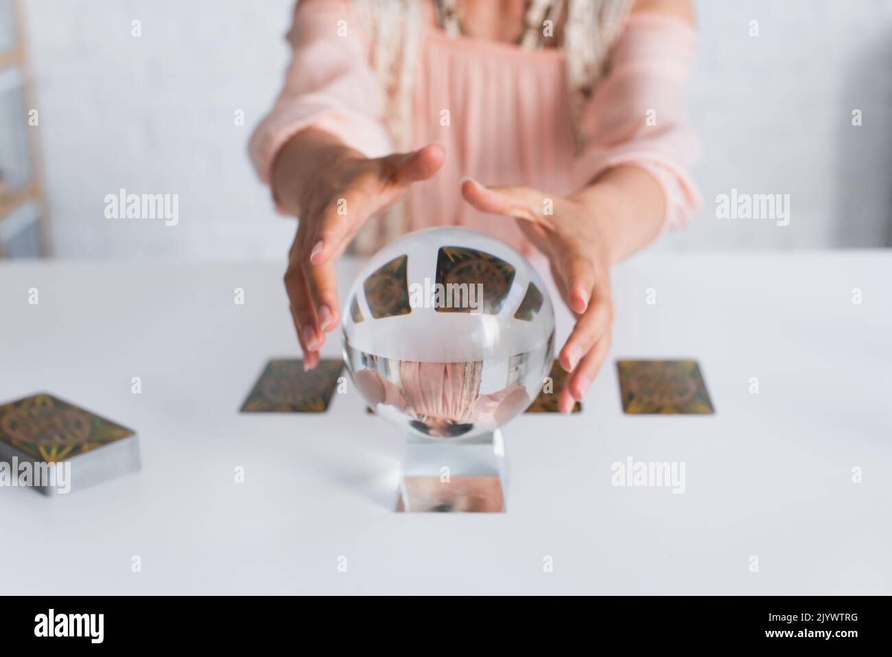 KYIV, UKRAINE - JUNE 29, 2022: selective focus of crystal ball near cropped fortune teller on blurred background Stock Photo