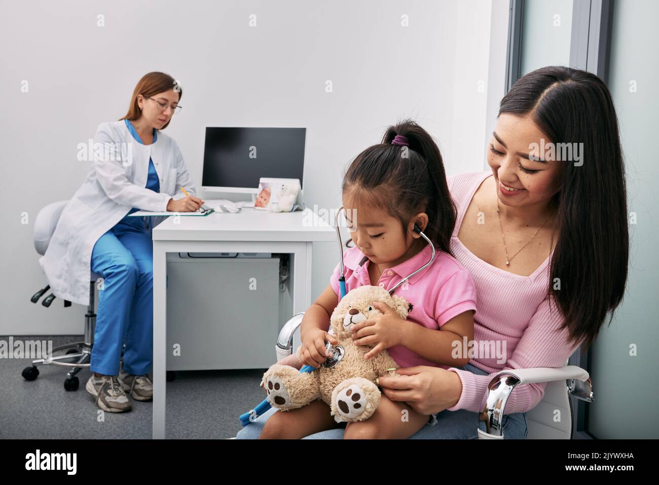 Consultation with pediatrician, kid health. Japanese little girl with her mother during a visit to child doctor Stock Photo