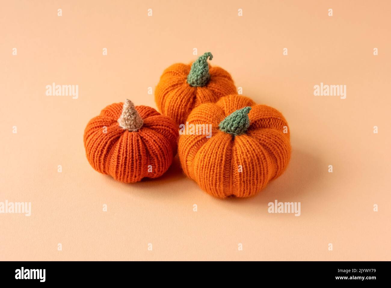 Knitted orange pumpkins on an orange background, autumn composition. Halloween concept. Stock Photo