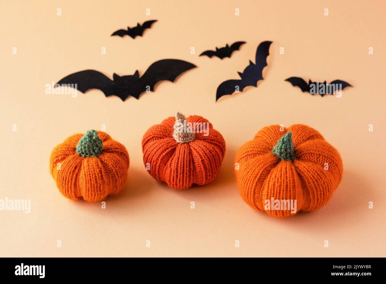 Knitted orange pumpkins and black bats on an orange background, autumn ...