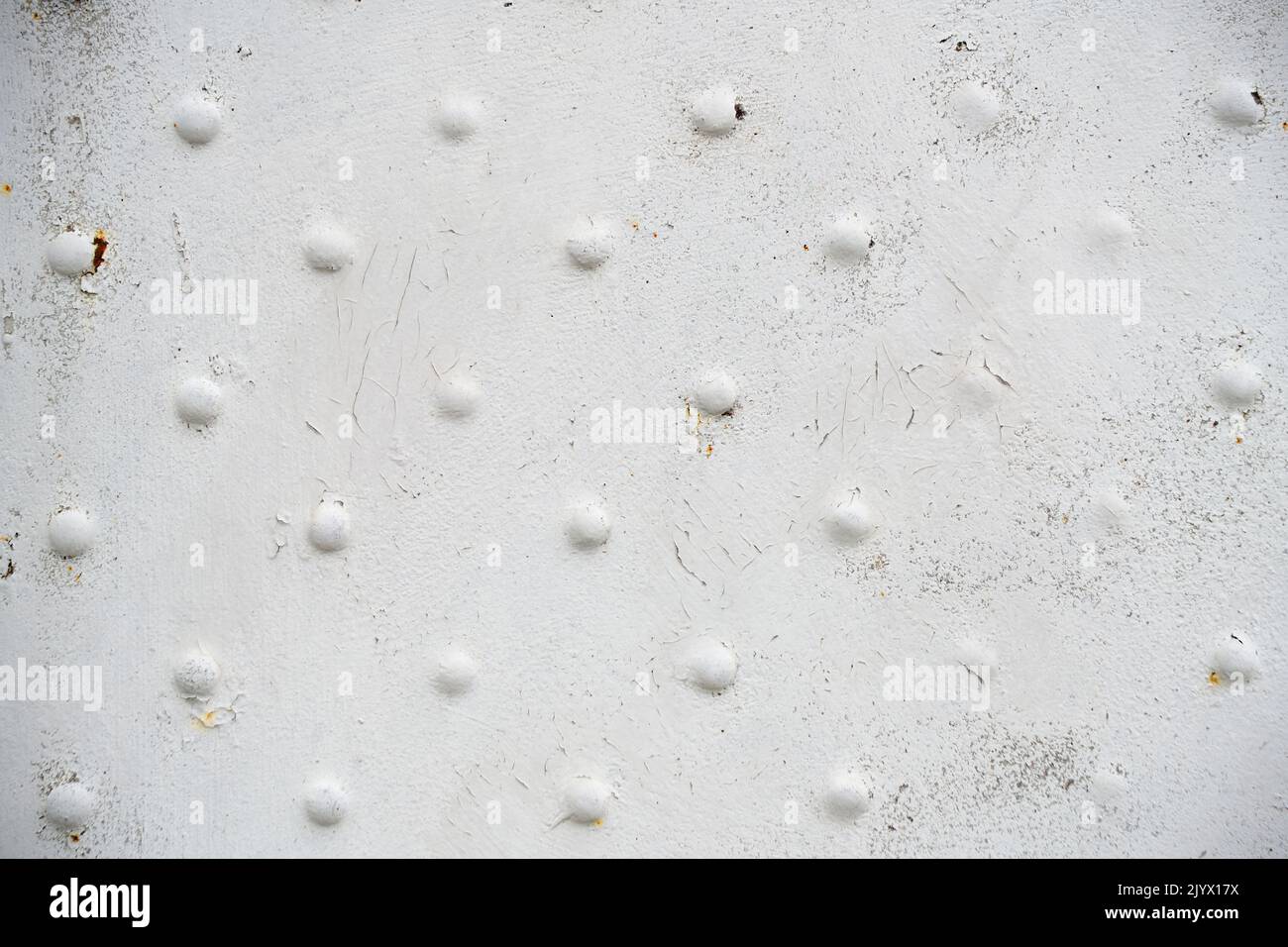 Old metal surface with rivets with white peeling paint Stock Photo