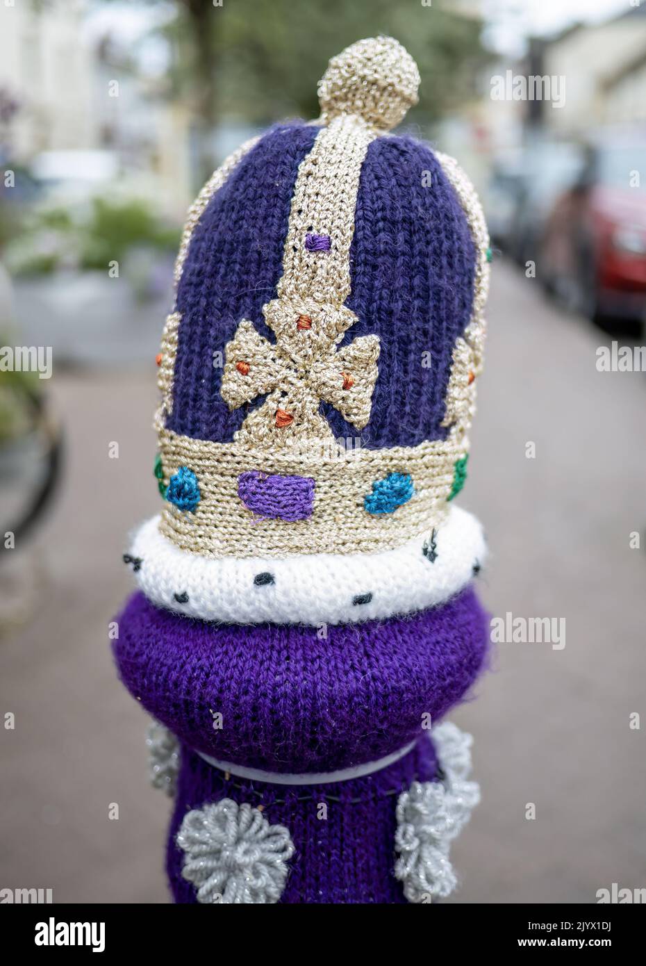 SOUTH MOLTON, DEVON, ENGLAND - AUGUST 2 2022: Post in street with knitted crown on top, yarn bombing. Stock Photo
