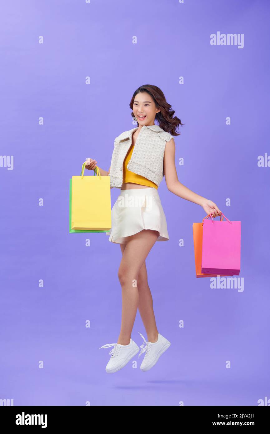Beautiful young woman with paper shopping bags on a purple background Stock Photo