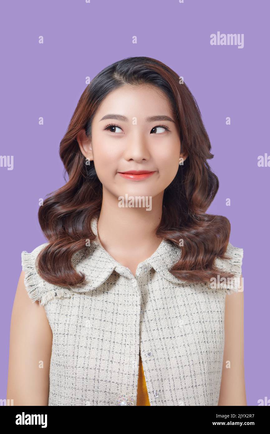 Young asian woman isolated on purple background making doubts gesture looking side Stock Photo