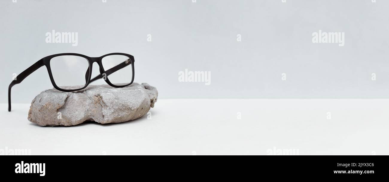 glasses on gray background with stone. glasses sale concept. Copy space for text. Optic store discount poster. Banner Stock Photo