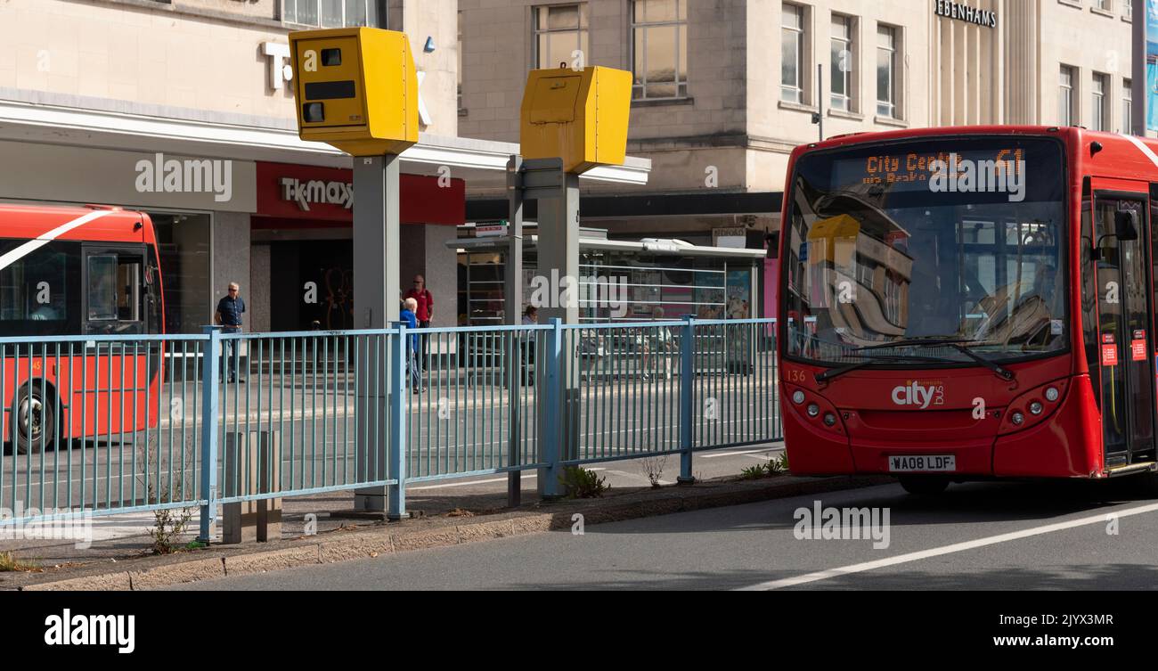 Plymouth, Devon, England, UK. 2022, Red city bus approaching two mounted speed cameras to record speed of approaching traffic. Stock Photo