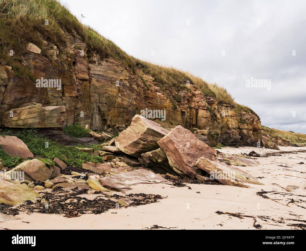 Coastal erosion illustrated by fallen sandstone cliffs at Cresswell beach in Northumberland, UK Stock Photo