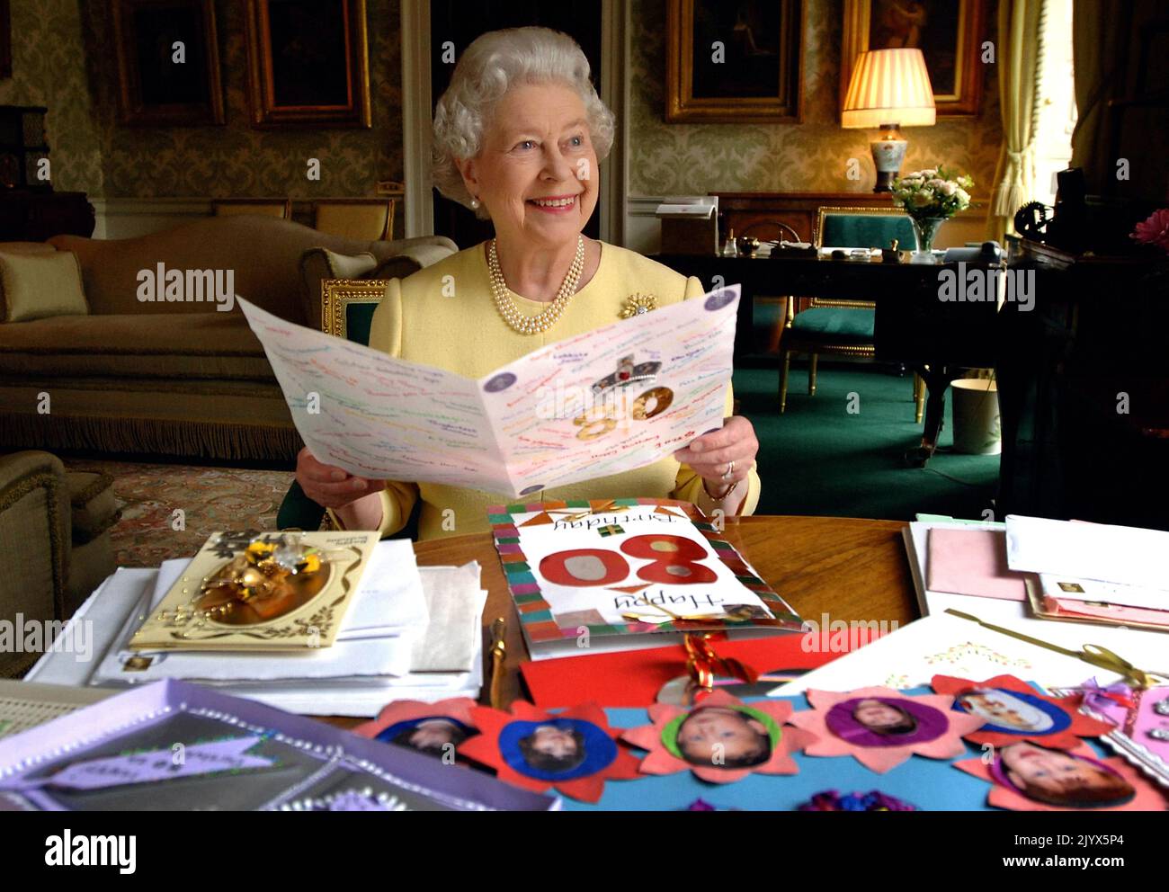 File photo dated 20/04/2006 of Queen Elizabeth II sitting in the Regency Room at Buckingham Palace in London as she looks at some of the cards which have been sent to her for her 80th birthday. The Queen died peacefully at Balmoral this afternoon, Buckingham Palace has announced. Issue date: Thursday September 8, 2022. Stock Photo