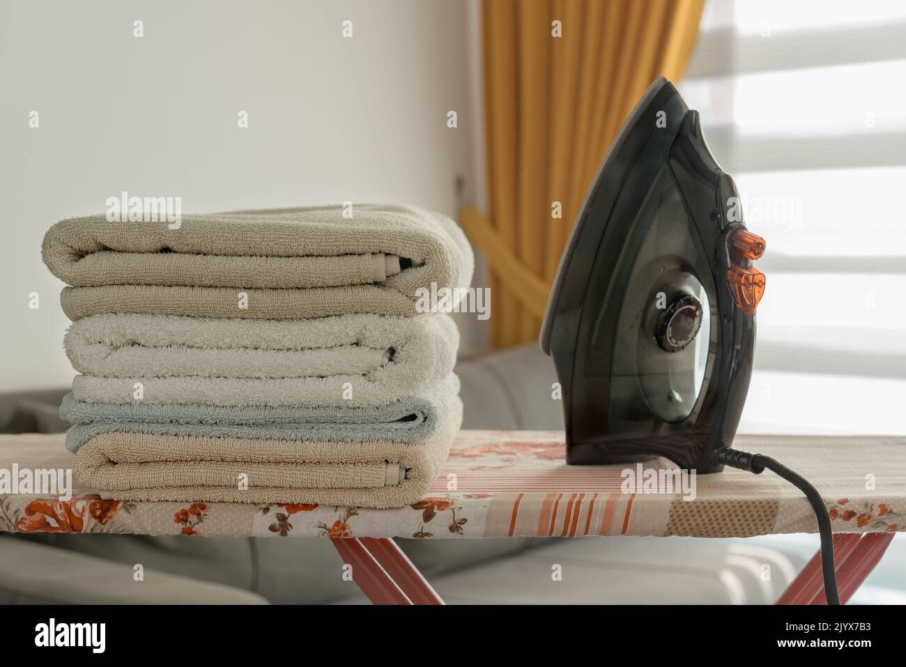 A pile of towels and an iron on the ironing board. Homework concept