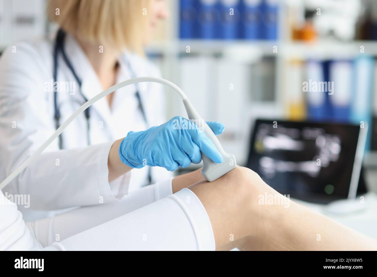 Orthopedic doctor makes ultrasound examination of patient knee in