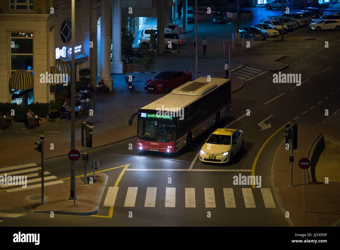 Dubai bus and taxi pause at a stoplight on a late night downtown