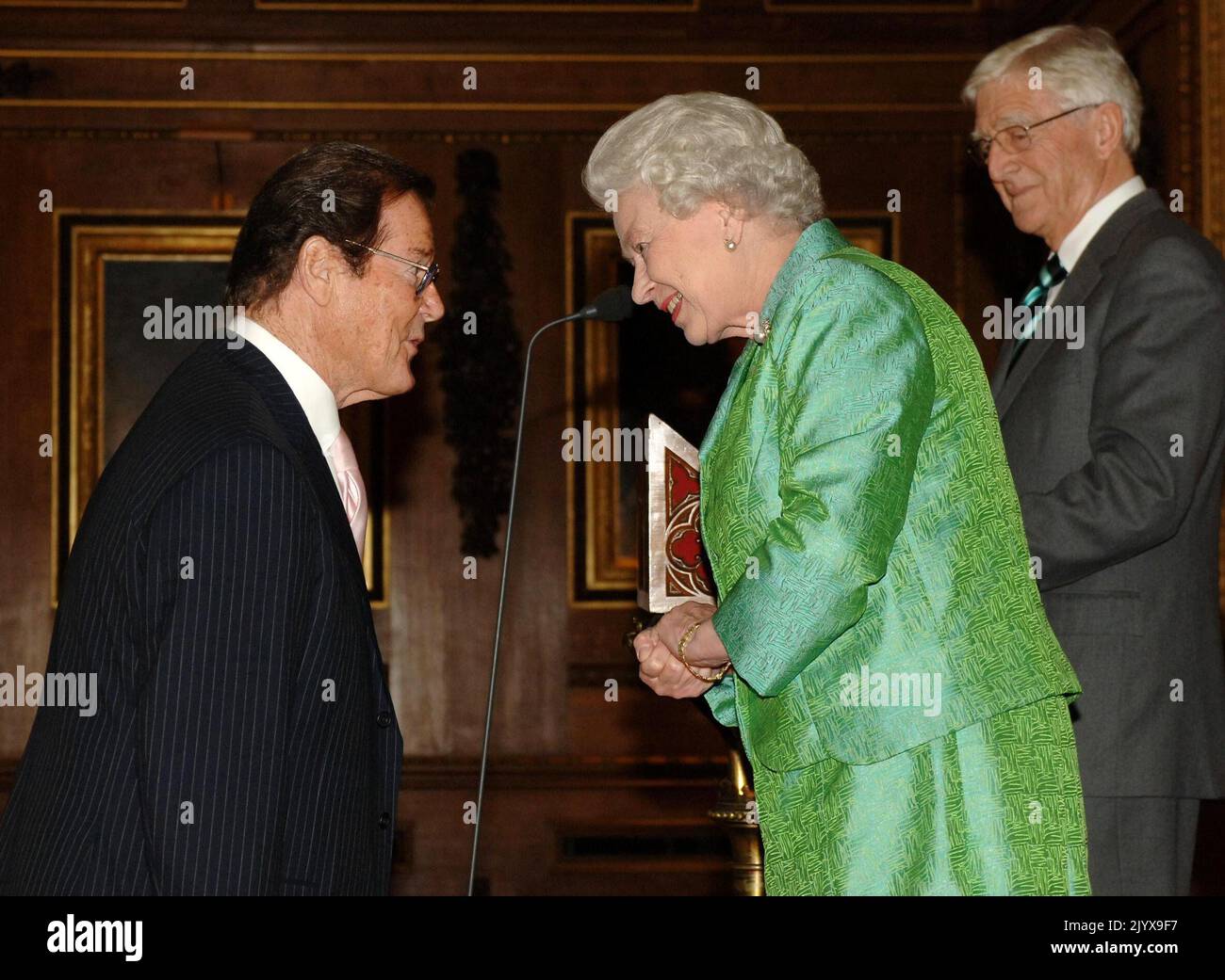 File photo dated 3/5/2006 of Queen Elizabeth II with Help The Aged Living Legend award winner, Sir Roger Moore, and 'compere', Michael Parkinson, right, at a ceremony at Windsor Castle. Issue date: Thursday September 8, 2022. The monarch was not fazed by celebrities and encountered hundreds of showbiz stars, pop legends and Hollywood greats over the decades, but many admitted to nerves on coming face to face with the famous long-reigning sovereign. Stock Photo