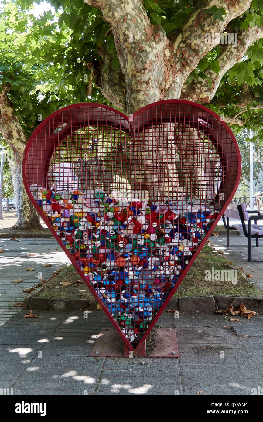 Heart-shaped container for recycling plastic caps. Selective focus. Upright photography. Stock Photo