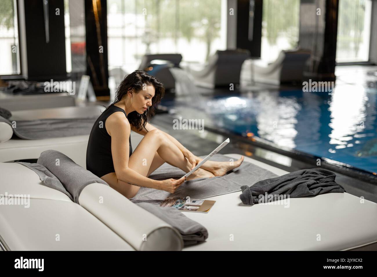 Woman rests by the swimming pool indoors at spa resort Stock Photo
