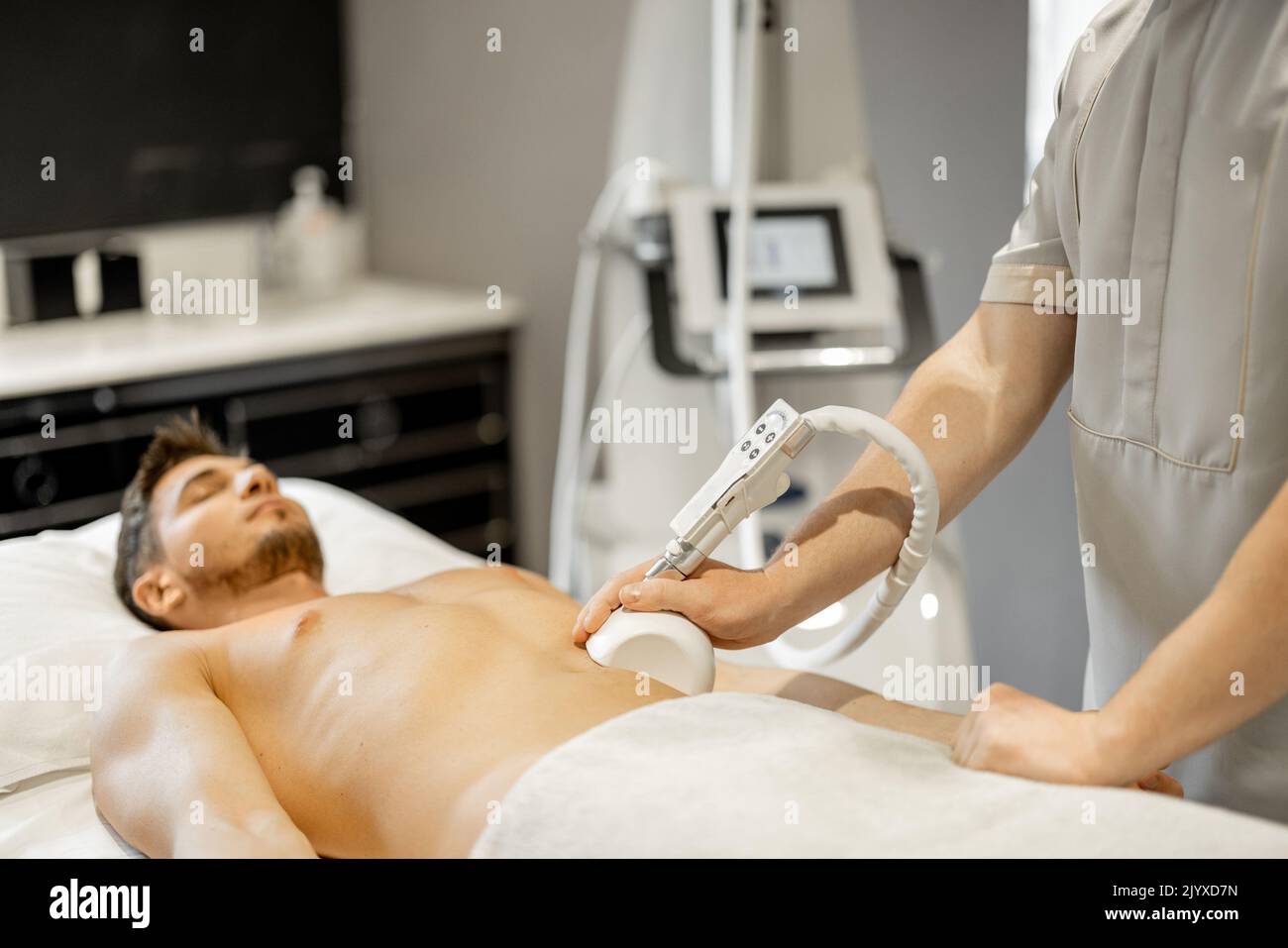 Man receiving vacuum roller massage on belly arrea at medical beauty centre. Lymphatic drainage massage procedure Stock Photo