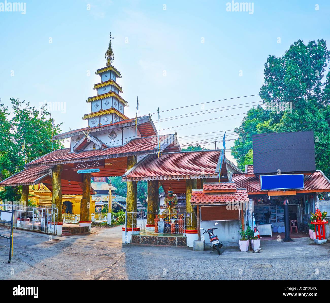 The scenic gate of Wat Klang Temple with a stupa-like roof, topped with hti umbrella with small bells, Pai, Thailand Stock Photo