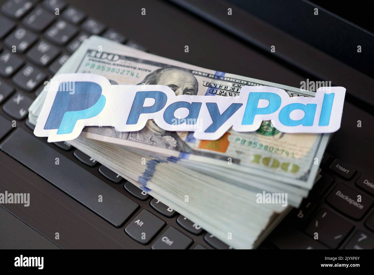 TERNOPIL, UKRAINE - SEPTEMBER 6, 2022 Paypal paper logotype lies on black laptop keyboard with US dollar bills. Payoneer is American financial service Stock Photo