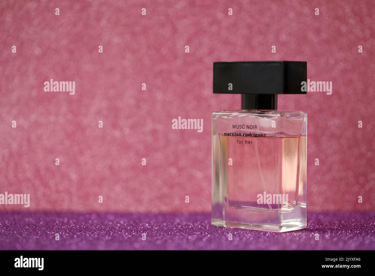TERNOPIL, UKRAINE - SEPTEMBER 2, 2022 Narciso Rodriguez Musc Noir perfume bottle on shiny glitter background in pink and purple colors Stock Photo
