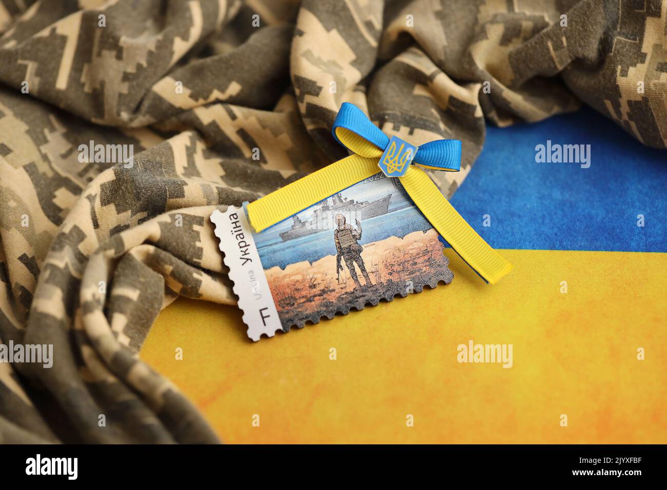 TERNOPIL, UKRAINE - SEPTEMBER 2, 2022 Famous Ukrainian postmark with russian warship and ukrainian soldier as wooden souvenir on army camouflage unifo Stock Photo