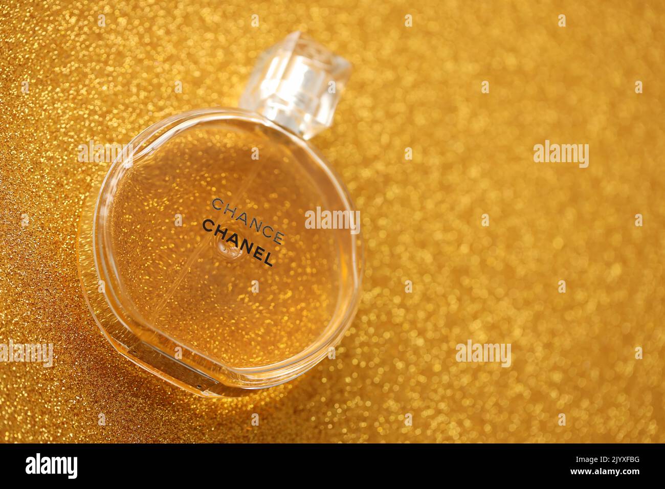 TERNOPIL, UKRAINE - SEPTEMBER 2, 2022 Chanel Chance worldwide famous french perfume bottle on shiny glitter background in golden and yellow colors Stock Photo