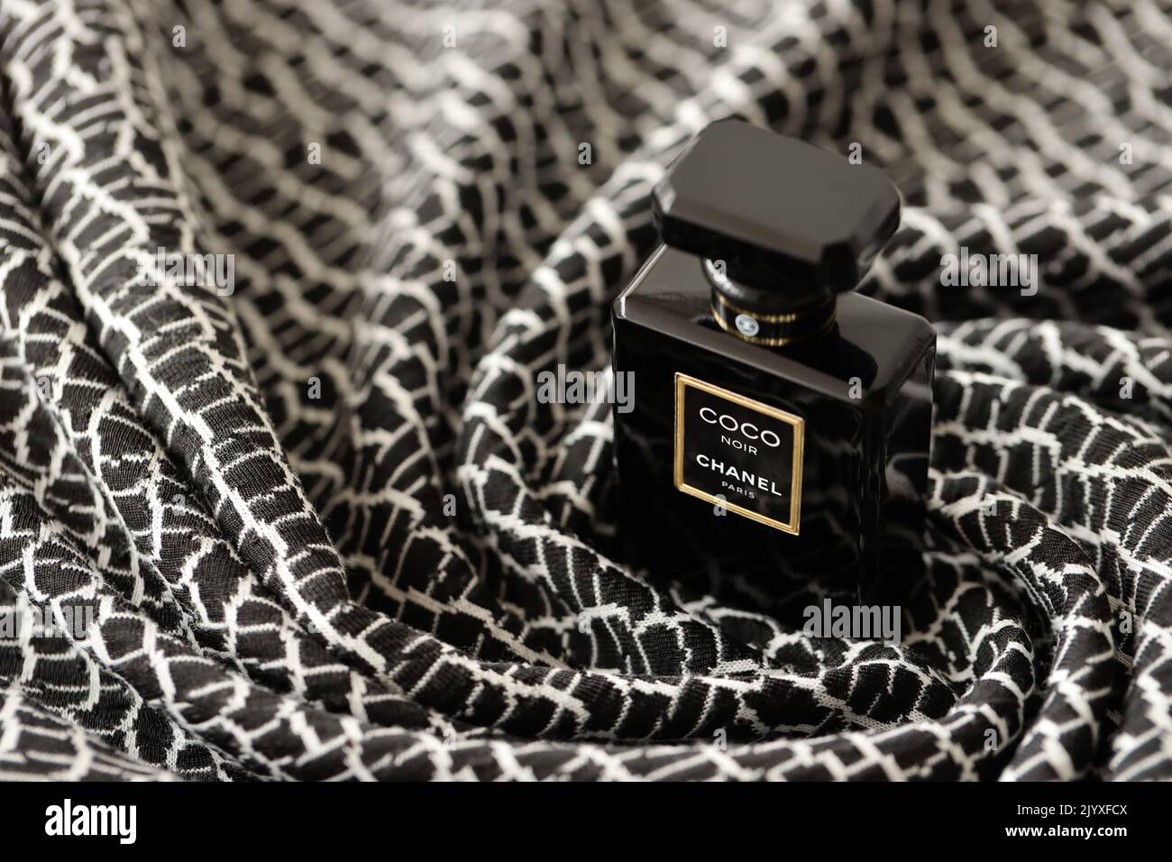 TERNOPIL, UKRAINE - SEPTEMBER 2, 2022 Coco Noir Chanel Paris worldwide famous french perfume black bottle on old plaid with monochrome pattern Stock Photo