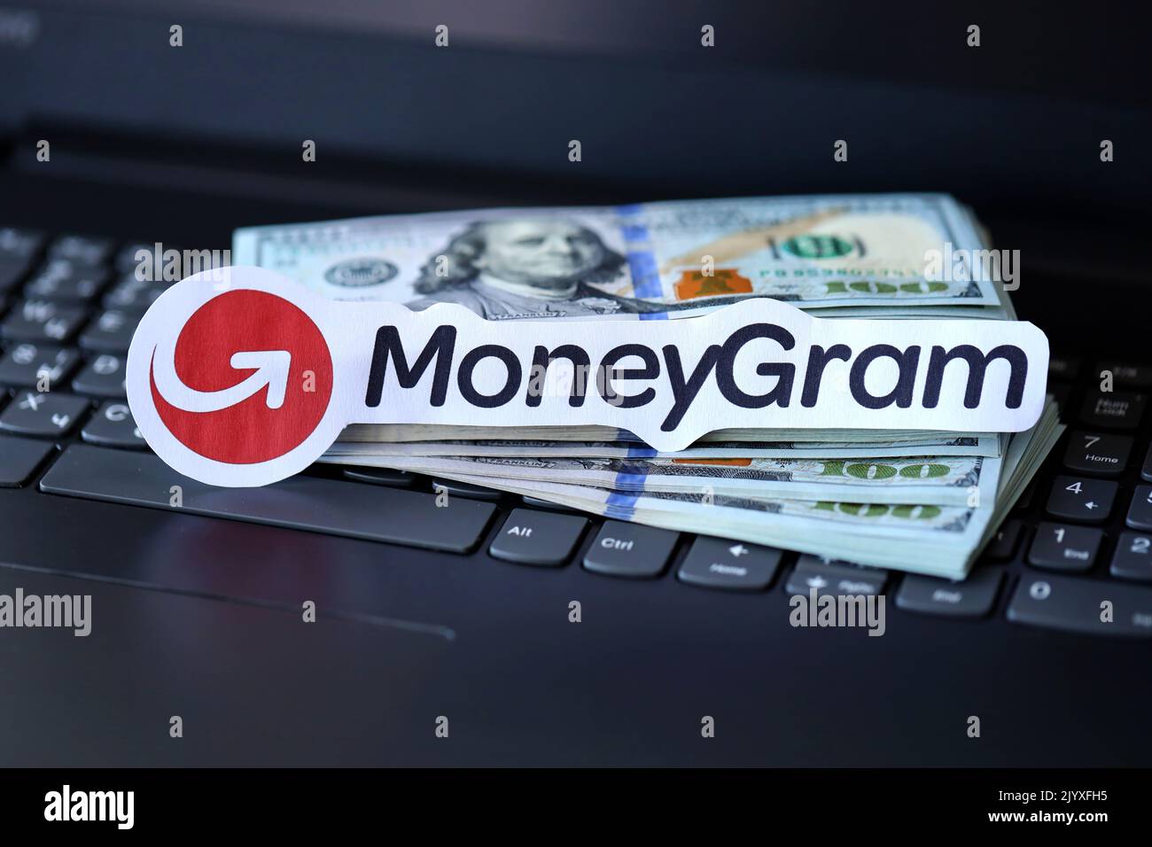 TERNOPIL, UKRAINE - SEPTEMBER 6, 2022 MoneyGram paper logotype lies on black laptop keyboard with US dollar bills. Moneygram is American cross border Stock Photo