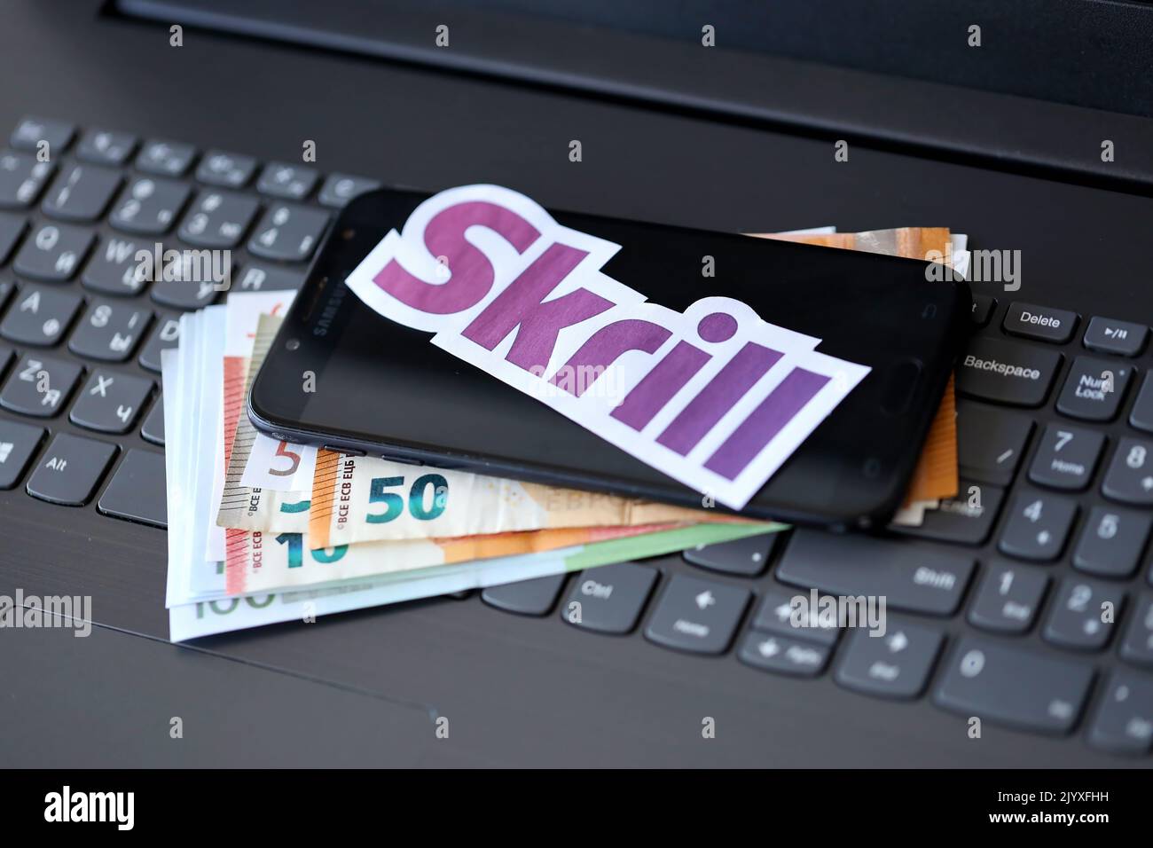 TERNOPIL, UKRAINE - SEPTEMBER 6, 2022 Skrill paper logotype lies on black laptop keyboard with euro bills. Payoneer is American financial services com Stock Photo