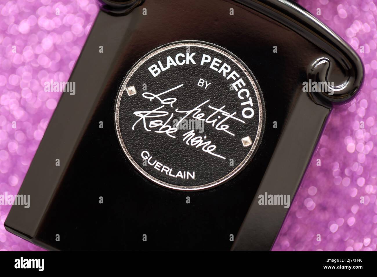 TERNOPIL, UKRAINE - SEPTEMBER 2, 2022 Black Perfecto La Petite Robe Noire by Guerlain perfume bottle on shiny glitter background in pink and purple co Stock Photo