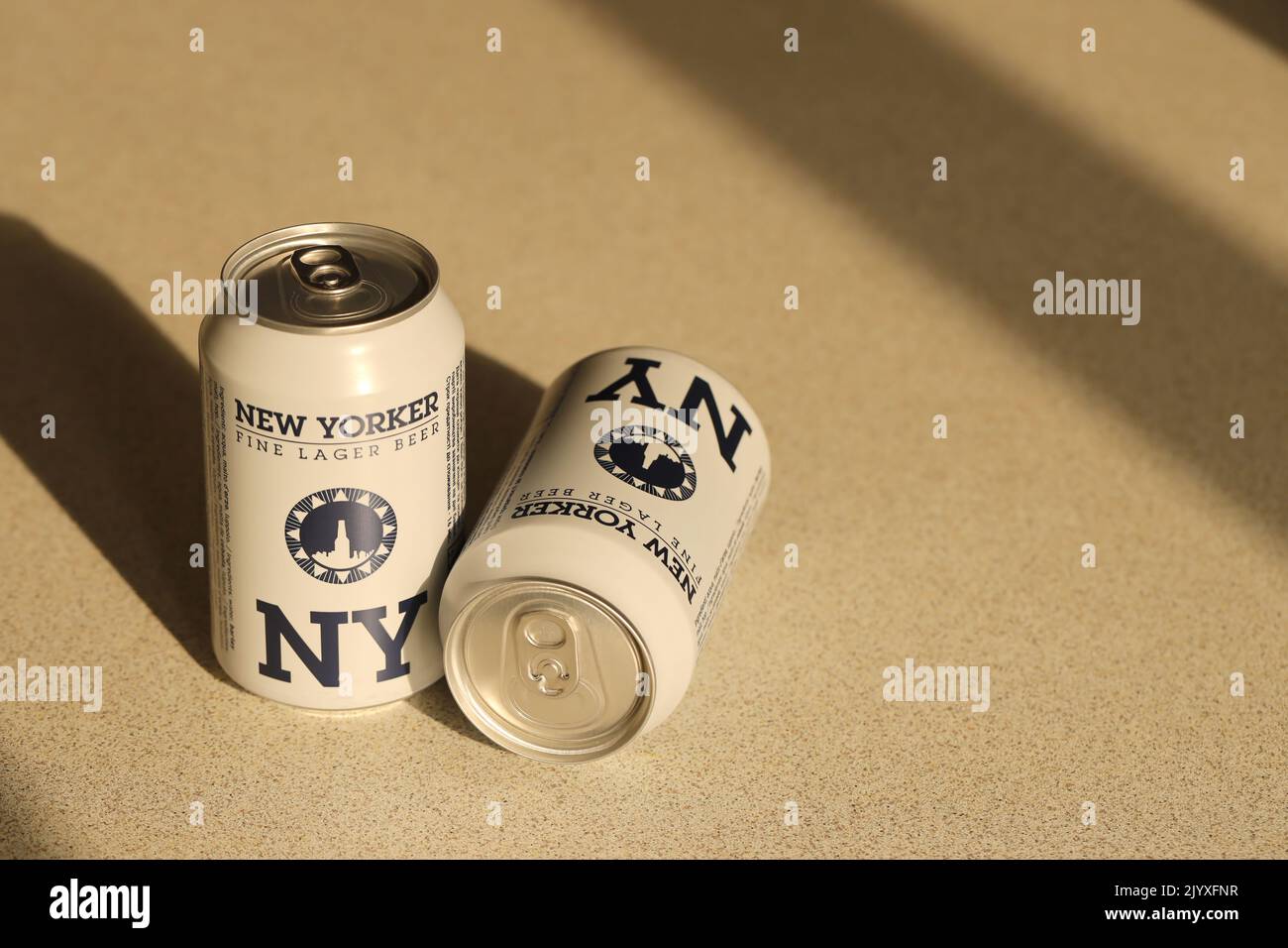 TERNOPIL, UKRAINE - JULY 18, 2022 Two cans of New Yorker fine lager beer with original logo and design on brown retro background surface Stock Photo