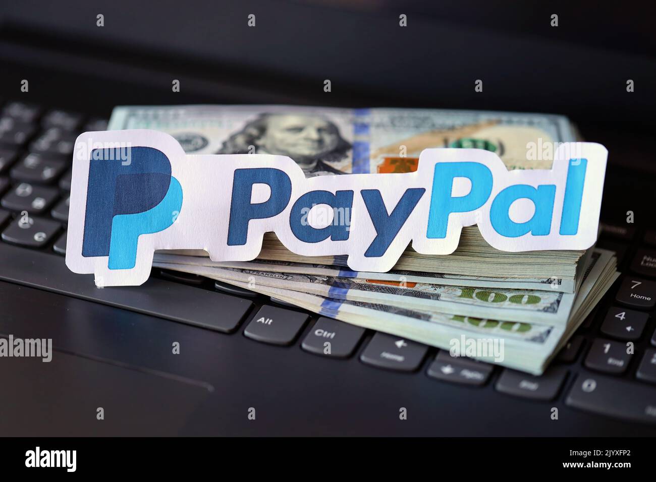 TERNOPIL, UKRAINE - SEPTEMBER 6, 2022 Paypal paper logotype lies on black laptop keyboard with US dollar bills. Payoneer is American financial service Stock Photo