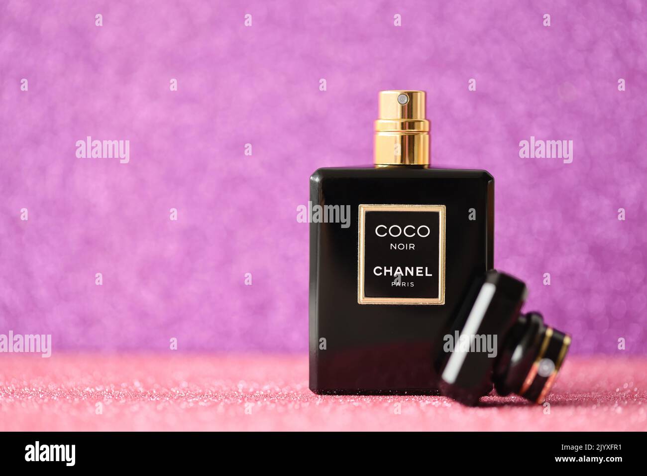 TERNOPIL, UKRAINE - SEPTEMBER 2, 2022 Coco Noir Chanel Paris worldwide famous french perfume black bottle on shiny glitter background in purple and pi Stock Photo