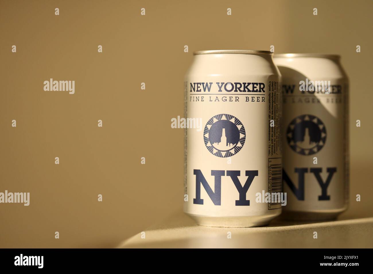TERNOPIL, UKRAINE - JULY 18, 2022 Two cans of New Yorker fine lager beer with original logo and design on brown retro background surface Stock Photo