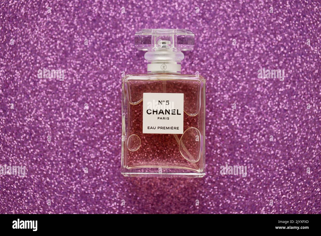 TERNOPIL, UKRAINE - SEPTEMBER 2, 2022 Chanel Number 5 Eau Premiere worldwide famous french perfume bottle on shiny glitter background in pink and purp Stock Photo