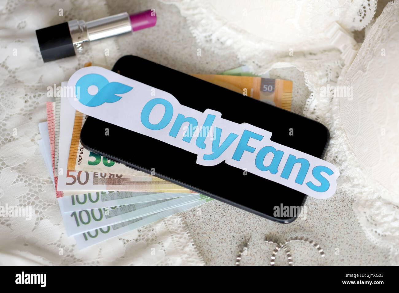 TERNOPIL, UKRAINE - SEPTEMBER 6, 2022 Onlyfans paper logotype among lipstick, earrings and women lingerie close to bunch of few euro bills Stock Photo