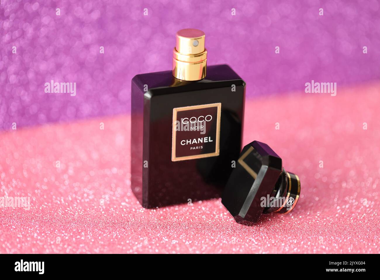 TERNOPIL, UKRAINE - SEPTEMBER 2, 2022 Coco Noir Chanel Paris worldwide famous french perfume black bottle on shiny glitter background in purple and pi Stock Photo