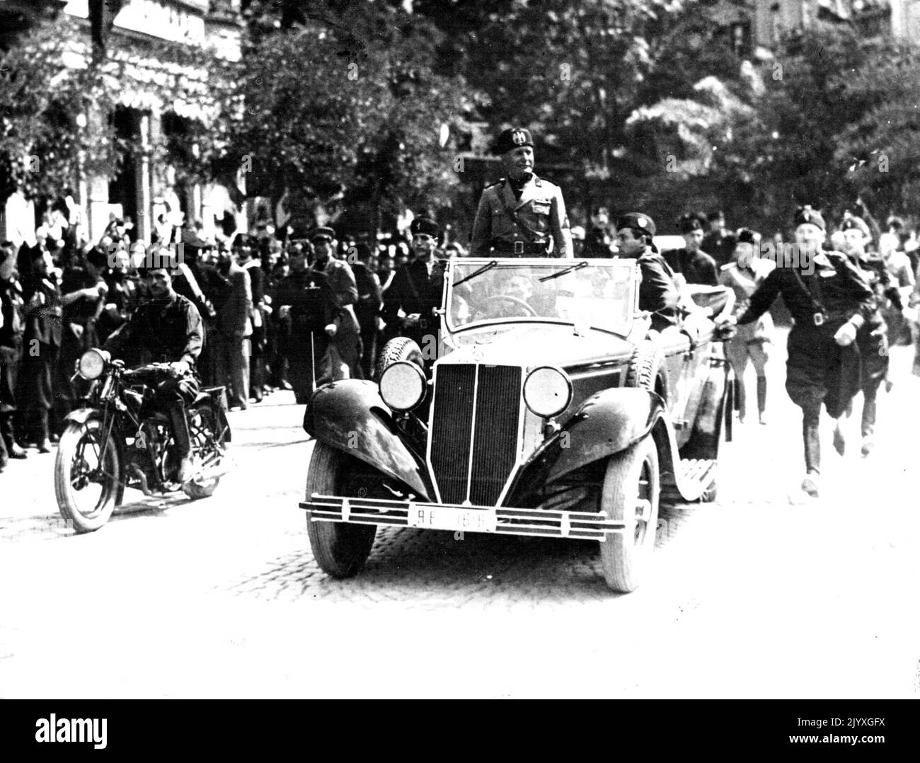 Enthusiastic Crowds Receive Mussolini to Meet His Cabinet Today - Signor Mussolini smiling as he surveyed the crowds, when he drove through the streets of Bolzano, the witness the great Manoeuvres, on Aug. 26. Signor Mussolini was received by cheering fascists as his car went slowly through the streets of Bolzano, on his arrival at the scene of the great Italian Manoeuvres the greatest peace-time Manooeuvres ever held in Europe, and in view of the strained situation between Italy and *****, the eyes of the worls are watching the activities intensely. The Duce is meeting members of his Cabinet Stock Photo